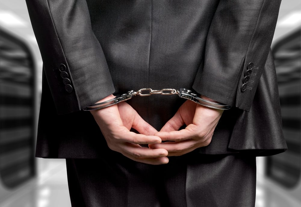 handcuffed man in suit photographed from the back