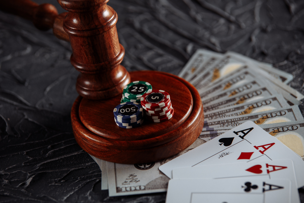 A wooden gavel with hundred-dollar bills, cards, and casino chips