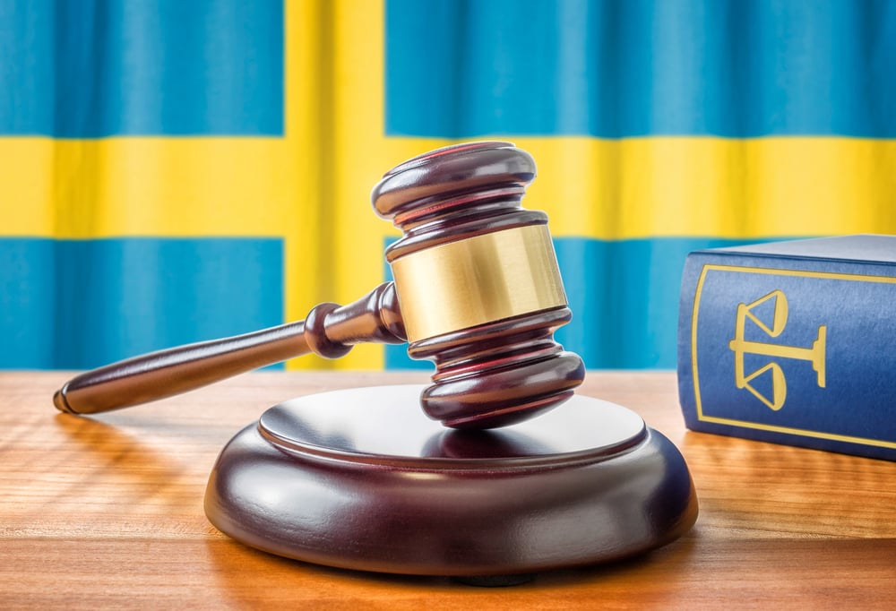 A judge's gavel in front of Swedish flag