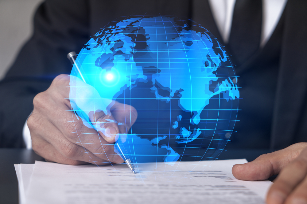 holographic image of the globe in front of businessman signing contract