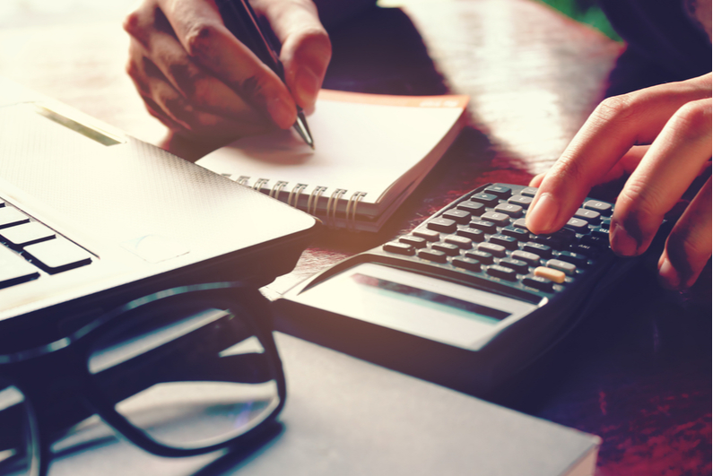 Closeup of a woman using a calculator and writing notes